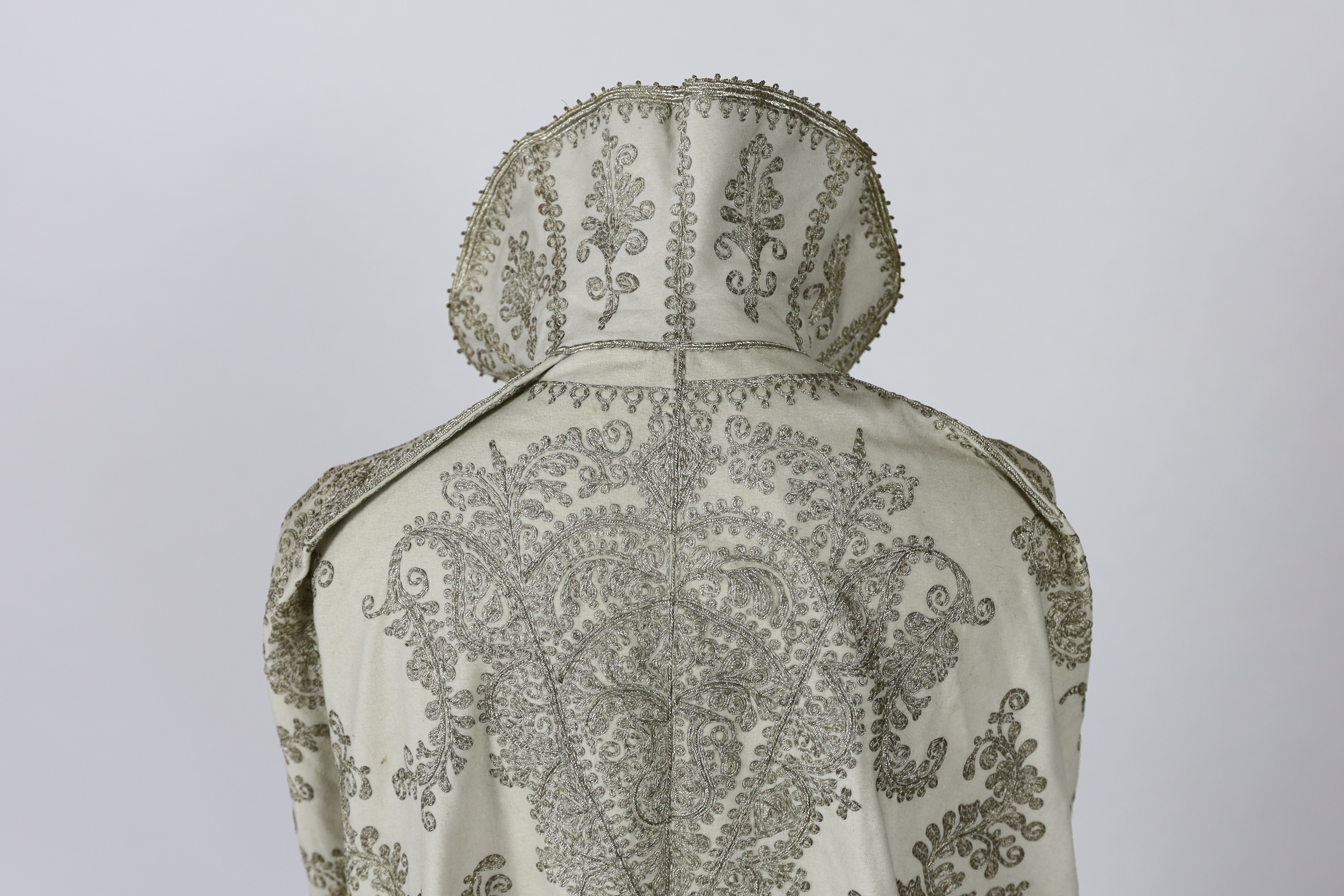 A 19th century Indian fine cream wool embroidered cape, probably made for the European market, embroidered in panels of silver metallic thread in an ornate vertical design with turquoise embellishments and lined in black